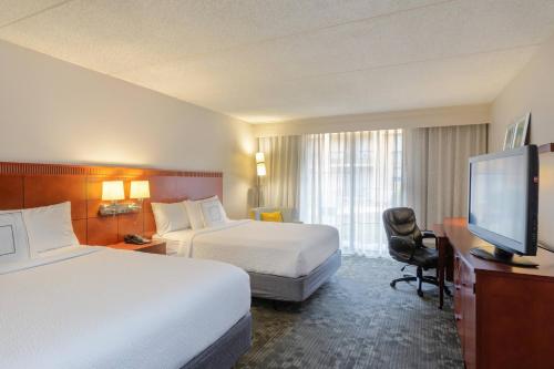 a hotel room with two beds and a flat screen tv at Courtyard by Marriott Atlanta Windy Hill/Ballpark in Atlanta