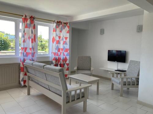 a living room with a bench and a tv at La Péninsule - Town Apartment No. 3 in Curepipe
