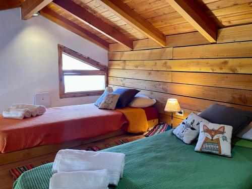 two beds in a room with wooden walls at Alewekehue , la linda in San Carlos de Bariloche