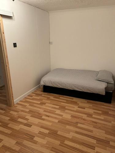 a bedroom with a bed and a wooden floor at Kelvin Gardens in Croydon