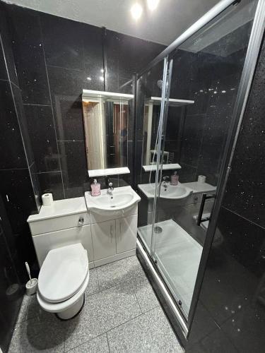 a bathroom with a toilet and a sink and a shower at Kelvin Gardens in Croydon