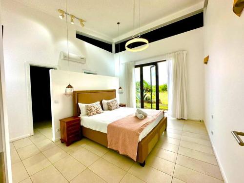 a bedroom with a bed and a large window at Avalon Golf Villa in Bois Chéri