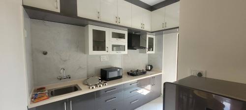a kitchen with white cabinets and a sink and a microwave at Castle HSR Sarjapur Road in Bengaluru