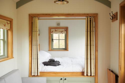 Woodmancote的住宿－Foot of the Downs Shepherds Hut，一间带镜子的卧室,床上配有一张床铺