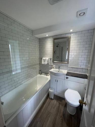 a bathroom with a tub and a toilet and a sink at The Bathurst Arms in Cirencester