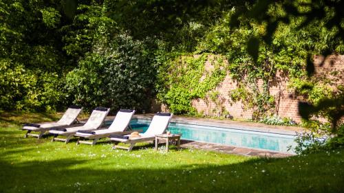 a row of lounge chairs next to a swimming pool at Guest house La Maison Chantecler in Brussels