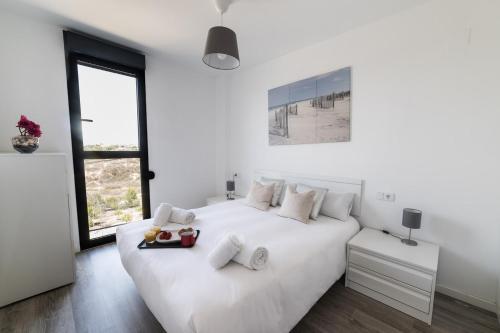 - une chambre blanche avec un grand lit blanc et des oreillers blancs dans l'établissement Apto. con piscinas y gym a 800 metros de playa, à El Campello