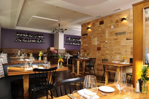 a restaurant with wooden tables and chairs and a brick wall at Hotel Stoller in Zürich