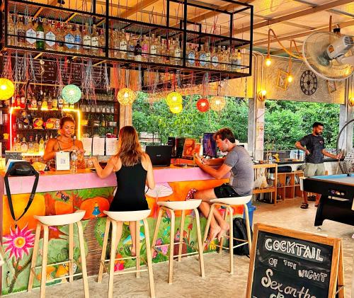 een groep mensen die aan een bar in een restaurant zitten bij Wonderland Jungle Hostel in Ko Tao