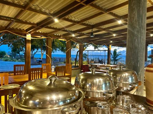 a row of metal pots on a table in a restaurant at Arasi Resort in Kalpitiya