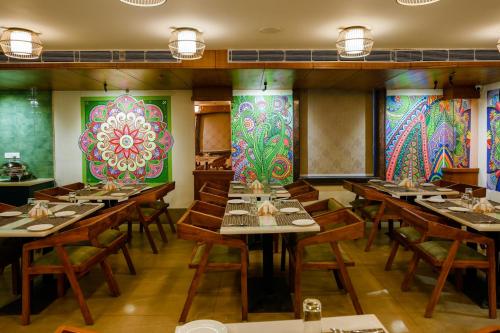 ein Restaurant mit Holztischen und farbenfrohen Wänden in der Unterkunft The Shivalik in Bhubaneshwar