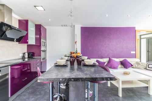 a kitchen with purple walls and a table and a couch at Villa de lujo. Piscina con jacuzzi. in Empuriabrava
