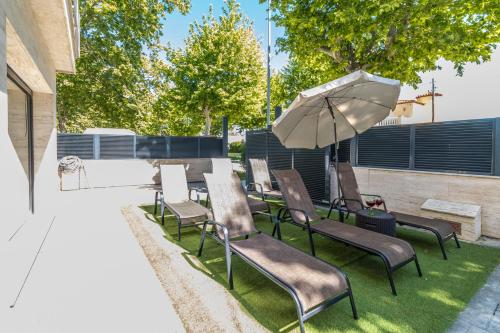 a group of chairs and an umbrella on the grass at Villa de lujo. Piscina con jacuzzi. in Empuriabrava