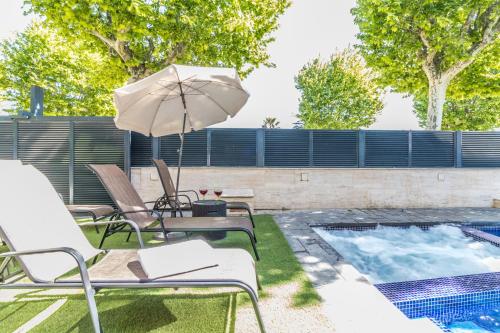 a patio with chairs and an umbrella next to a swimming pool at Villa de lujo. Piscina con jacuzzi. in Empuriabrava