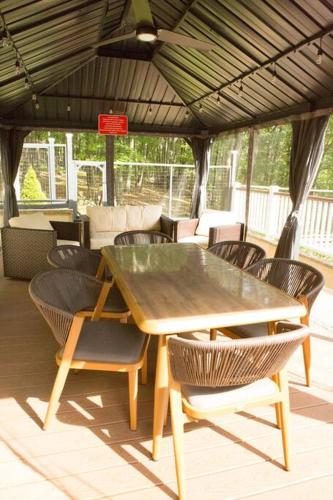 a wooden table and chairs on a patio at Luxury getaway in woods, Jacuzzi, Hot Tub, Pool in Bushkill