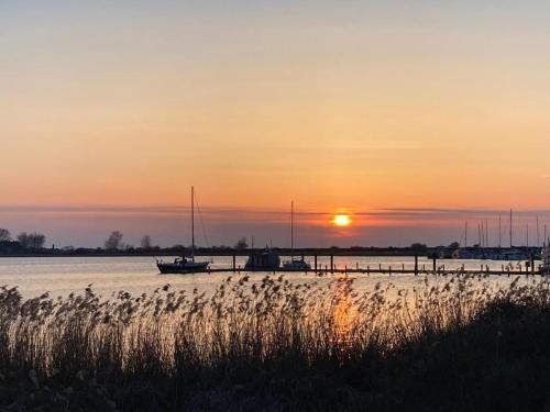 a sunset over a body of water with boats at Gemütliche FeWo mit Balkon nahe der Ostsee - 2 Schlafzimmer in Wischuer