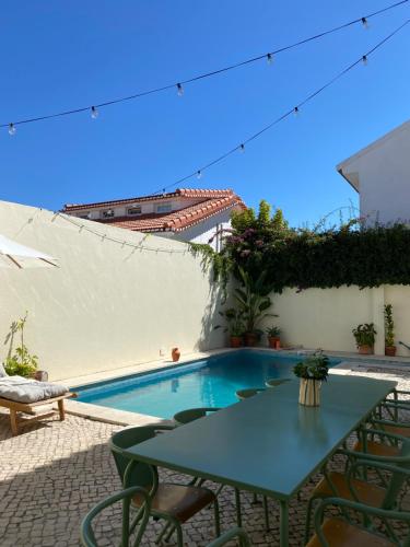 eine Terrasse mit einem Tisch, Stühlen und einem Pool in der Unterkunft Beach house upscale villa with pool in Costa da Caparica