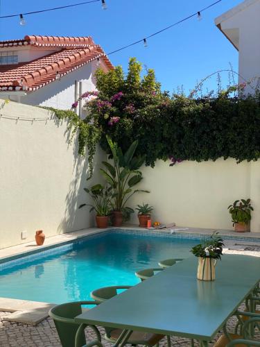 a table and chairs next to a swimming pool at Beach house upscale villa with pool in Costa da Caparica