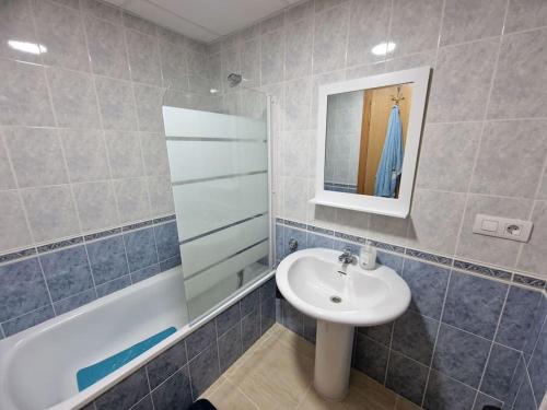 a bathroom with a sink and a mirror and a tub at Apartamento vacacional in Torreblanca
