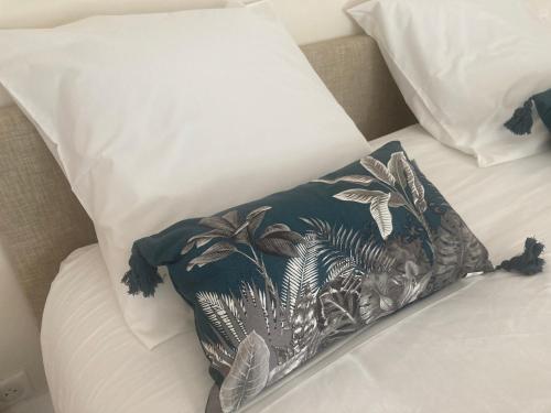 a pillow on top of a bed with white pillows at LE MAS de PAUL in Saint-Julien-de-Cassagnas