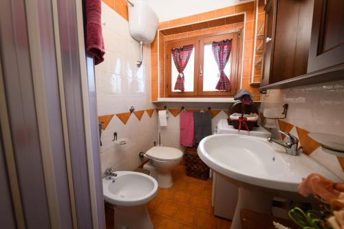 a bathroom with two sinks and a toilet and a window at La Pineta di Giove - Casa Lory in Campo di Giove