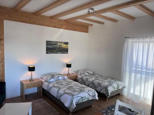EngelsbrandにあるFerienwohnungen Auf der Höheの白い壁と木製の天井が特徴の客室で、ベッド2台が備わります。