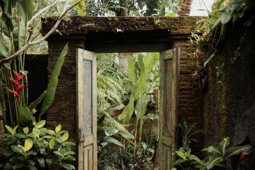 an old wooden door in a garden with plants at Moringa Ubud Villa in Ubud