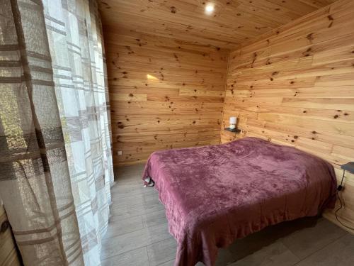 1 dormitorio con 1 cama en una cabaña de madera en Chalet contemporain ( chalet 2), en Montauban