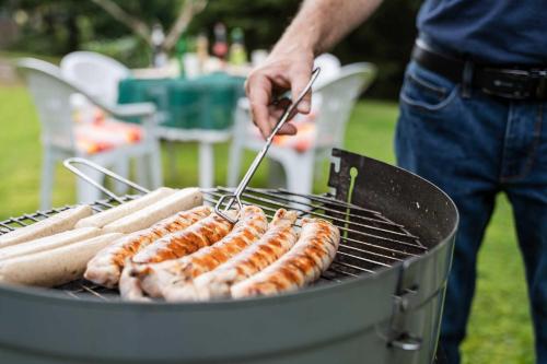 a man is cooking hot dogs on a grill at Pension Zum Hexenstieg in Schierke