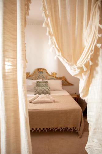 a bedroom with a canopy bed with curtains at Dar Shams - Les Houchs De Djerba in Erriadh