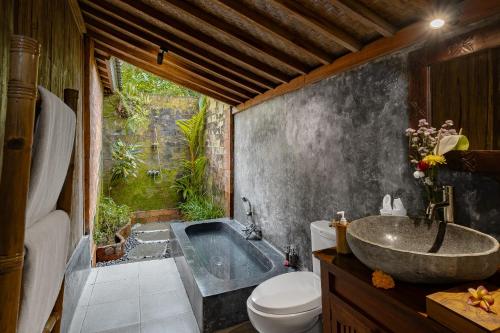 a bathroom with a tub and a toilet and a sink at Moringa Ubud Villa in Ubud