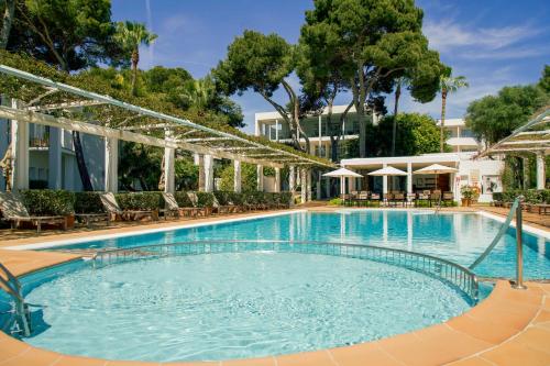una piscina in un resort con sedie e ombrelloni di Melia Cala d'Or Boutique Hotel a Cala d´Or