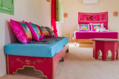 a room with two beds and a couch with colorful pillows at Dar Shams - Les Houchs De Djerba in Erriadh