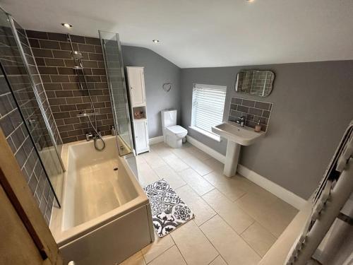 a bathroom with a tub and a toilet and a sink at Two Bed Charming Cottage in Crewe