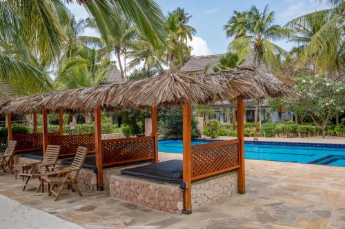 een resort met een zwembad en een rieten parasol en stoelen bij Michamvi Sunset Bay in Michamvi