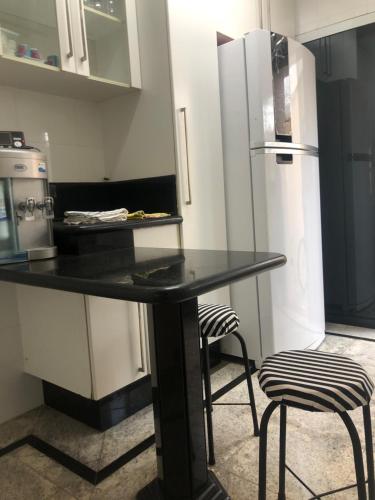 a kitchen with a black counter and a refrigerator at Quarto com varanda tipo Airbn b Vista Panorâmica Livre da Cidade in Americana