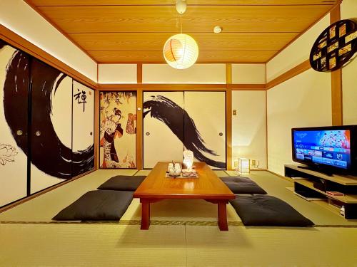 a living room with a table and a tv at guesthouse森之宮【青丸】 in Osaka