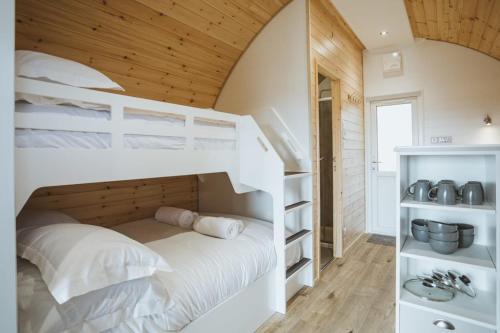 a bedroom with a white bunk bed and a staircase at Carlton Manor Pods in Aldbrough