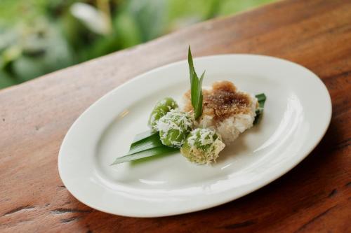 a white plate with food on a wooden table at Moringa Ubud Villa in Ubud