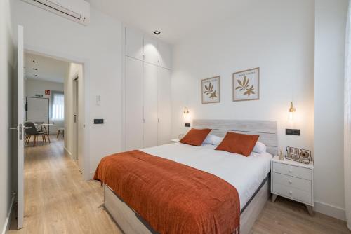 um quarto branco com uma cama grande com lençóis laranja em JES Apartment A Nuevos Ministerios em Madri