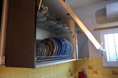 a cupboard filled with plates and dishes in a kitchen at House with sea breeze-Anemelia in Nafplio
