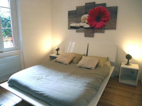 um quarto com uma cama com uma flor vermelha na parede em Appartement Université-Capitole em Toulouse