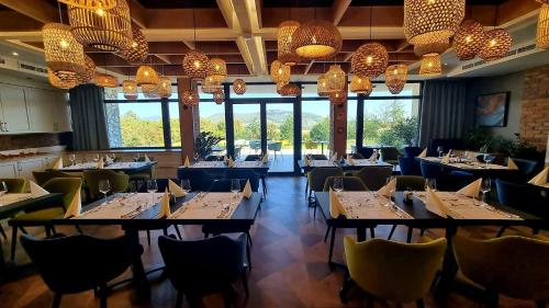 a dining room with tables and chairs and chandeliers at Hotel Kőporos Hercegkút in Hercegkút