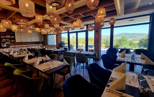 a restaurant with tables and chairs and large windows at Hotel Kőporos Hercegkút in Hercegkút