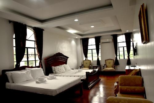 Mamburao的住宿－Isla De Oro Hotel，一间卧室设有两张床、一张沙发和窗户。