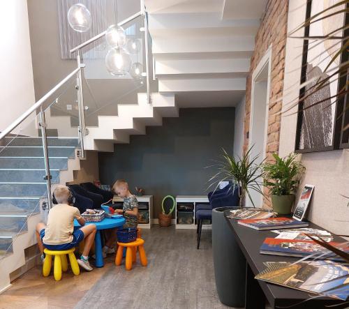 two people sitting at a table in a room with a staircase at Hotel Kőporos Hercegkút in Hercegkút