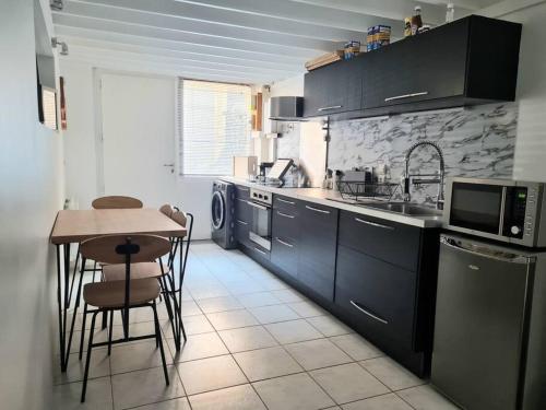 une cuisine avec des armoires noires et une table avec des chaises dans l'établissement Duplex atypique loft Lyon 6, à Lyon
