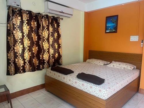 a bedroom with a bed and a window with curtains at Urbban Castle in Port Blair