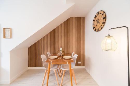 a dining room with a table and chairs and a clock at Spacieux T2 proche plages côte de granite rose in Trébeurden