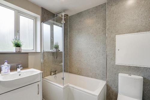 a bathroom with a tub and a sink and a toilet at Lilac Cottage in Parkend